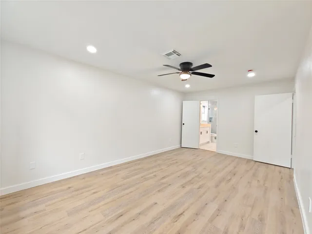 a view of empty room with wooden floor and ceiling fan