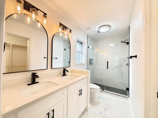 a bathroom with a double vanity sink toilet mirror and shower