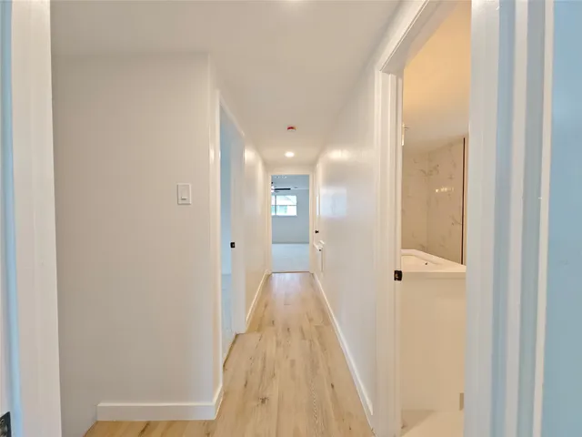 a view of a hallway with wooden floor and a bathroom