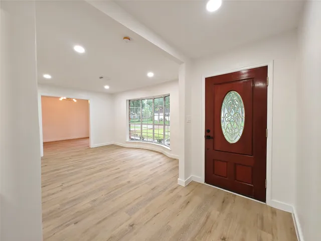 a view of an empty room with a window and wooden floor