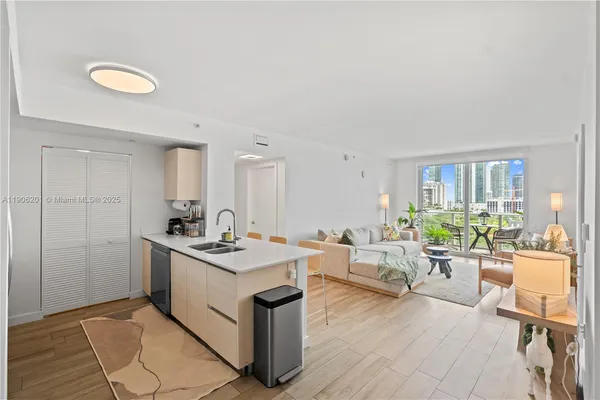 a living room with stainless steel appliances granite countertop a sink and a refrigerator