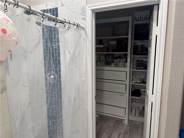 a walk in closet with wooden floor