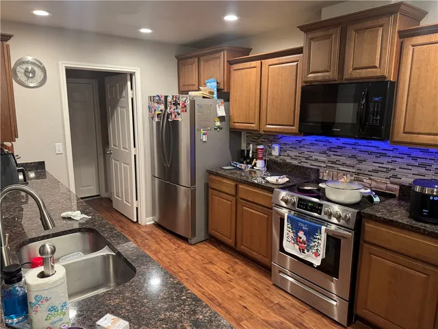 a kitchen with stainless steel appliances granite countertop a refrigerator stove and sink