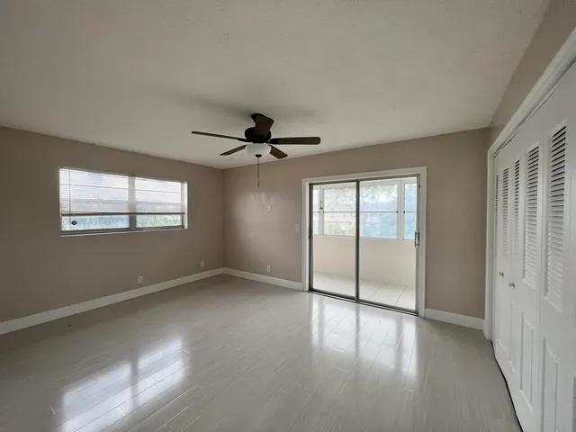an empty room with chandelier fan and windows