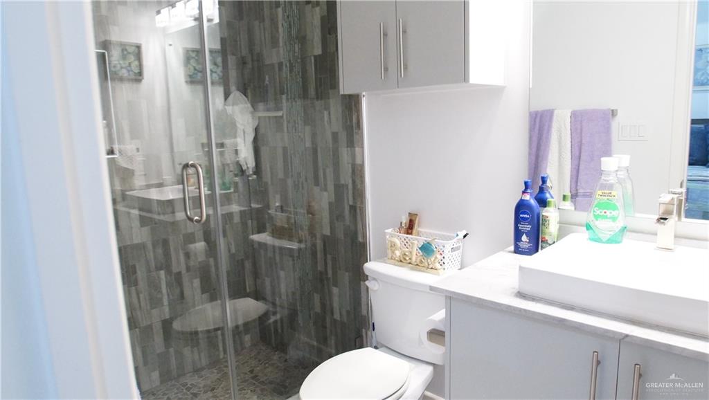 414 Ric Mar Street Edinburg, TX 78541 - Photo 31 of 36 Spacious bathroom featuring a glass-enclosed shower with textured wall tile and a built-in bench