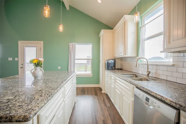 a kitchen with granite countertop sink and cabinets