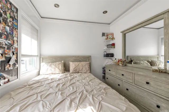 a bedroom with a large bed and a large mirror next to a window