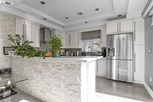 a kitchen with stainless steel appliances a refrigerator a sink a stove a washer dryer and white cabinets