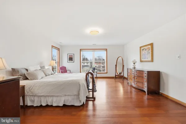 a bedroom with a bed and dresser with wooden floor
