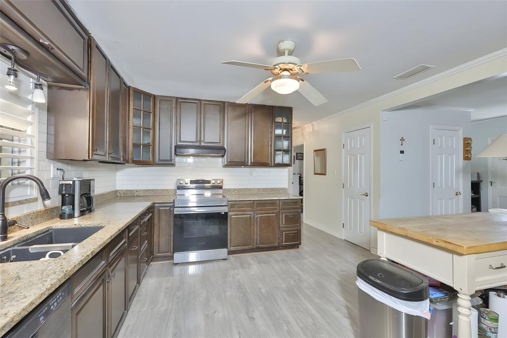 14451 Highland Road Wimauma, FL 33598 - Photo 53 of 80 a kitchen with kitchen island granite countertop a sink cabinets and stainless steel appliances
