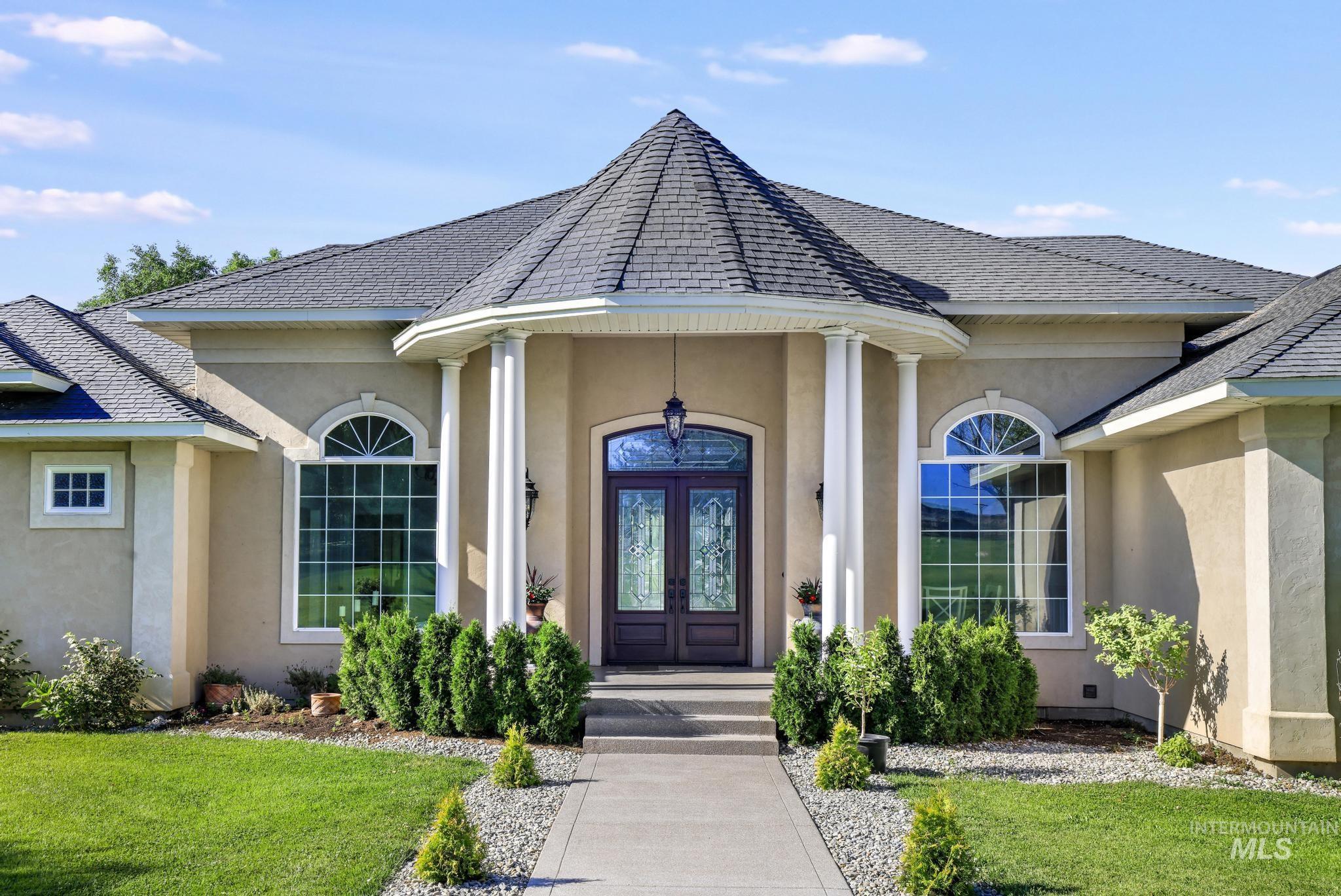 1301 Kanaka Rapids Road Buhl, ID 83316 - Photo 5 of 50 Stucco exterior with a prominent turret entry, double arched entry doors, and a concrete walkway