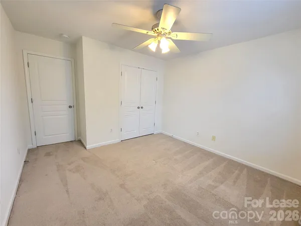 an empty room with a chandelier fan and windows