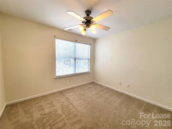 an empty room with a window and a ceiling fan