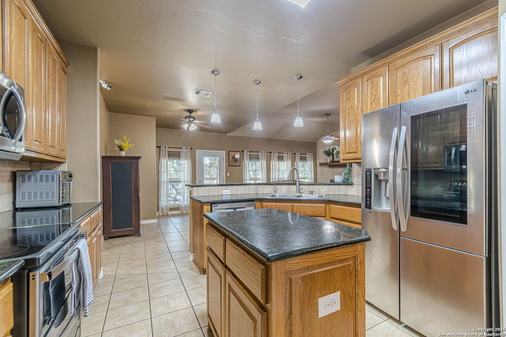 249 Lakeridge Loop Lakehills, TX 78063 - Photo 13 of 50 a kitchen with stainless steel appliances granite countertop a refrigerator a oven and a sink