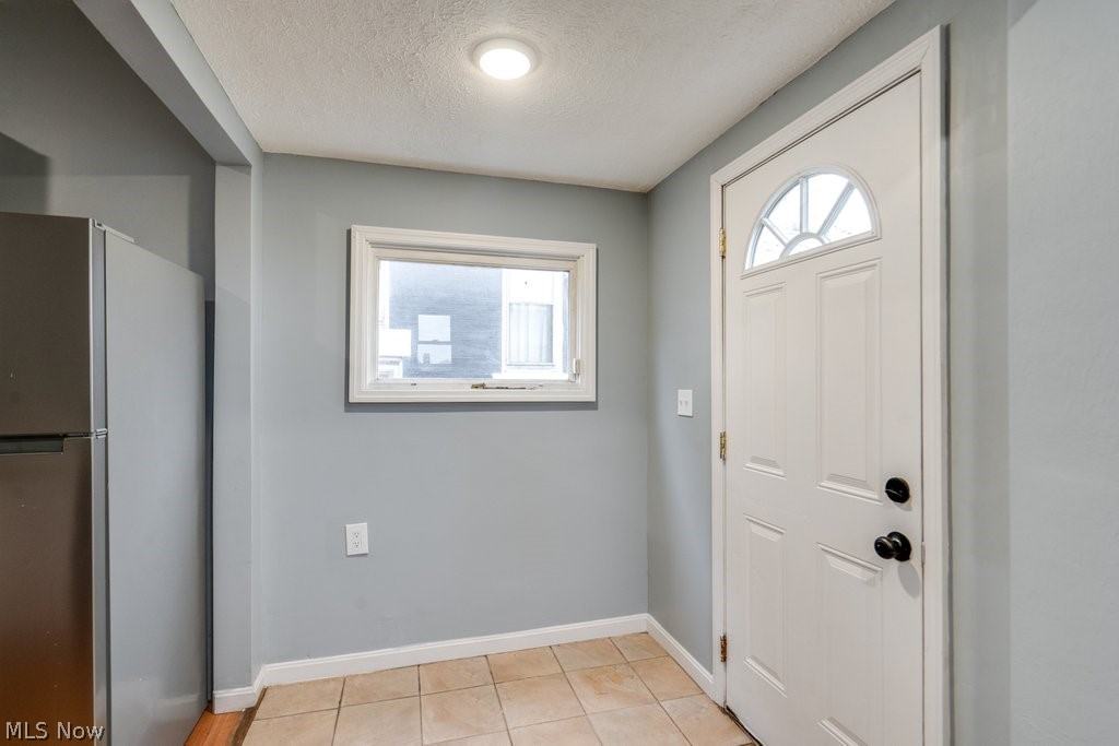 1607 9th Street Southwest Canton, OH 44706 - Photo 22 of 41 Entryway featuring a white paneled door with an arched glass insert, light blue walls, and tiled flooring