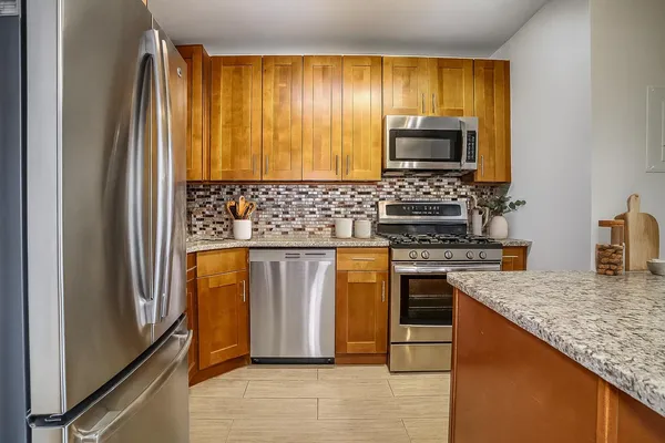 a kitchen with stainless steel appliances granite countertop a stove top oven microwave and refrigerator