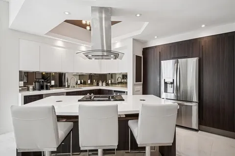 a kitchen with stainless steel appliances kitchen island granite countertop a dining table chairs and a refrigerator