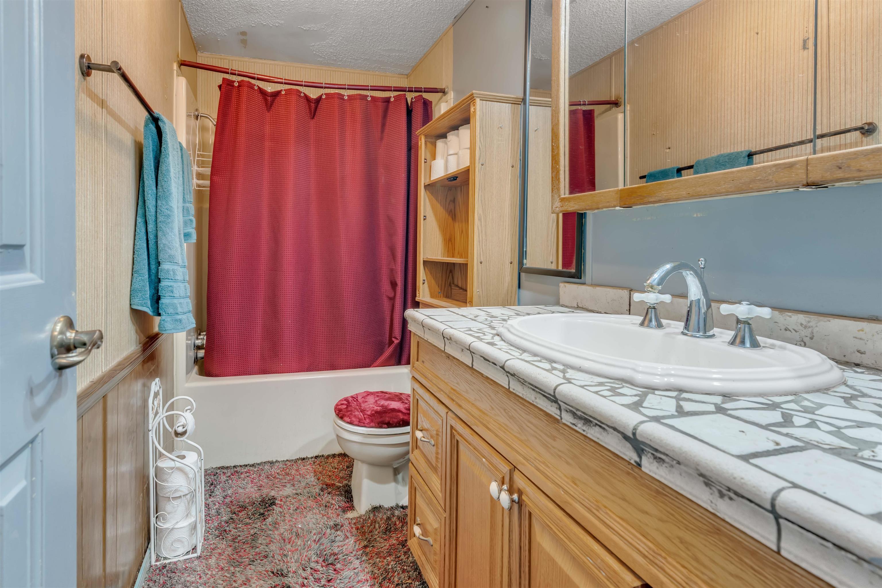 Built-in vanity with mosaic tile countertop, chrome faucet, and integrated sink
