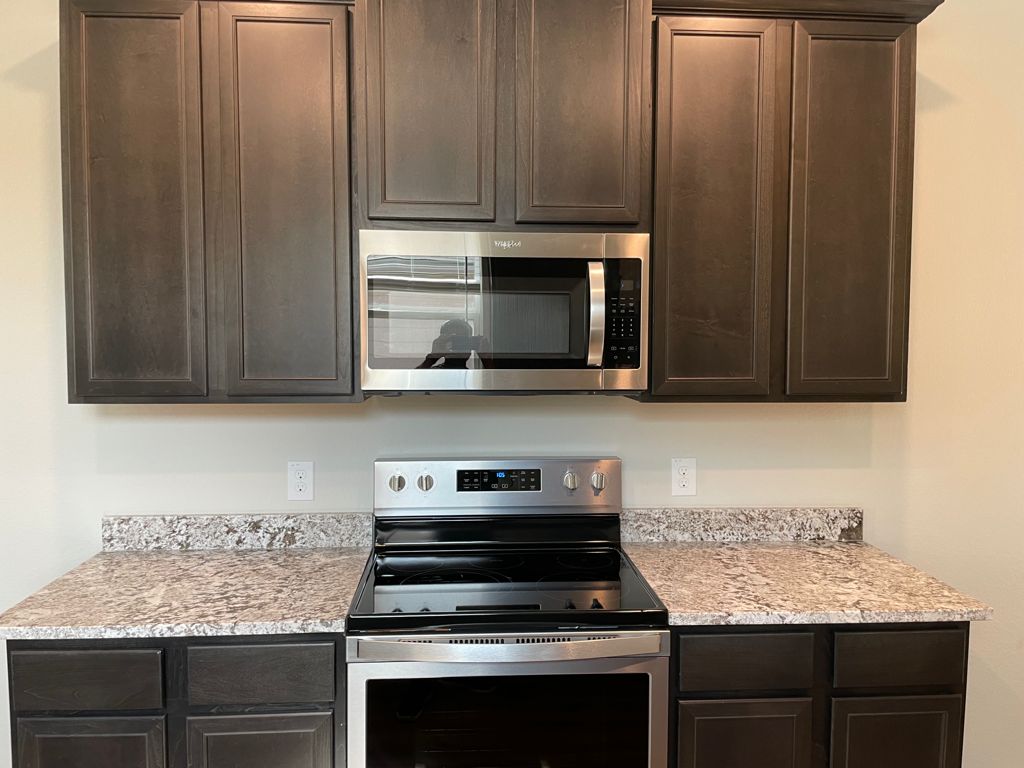 109 Declaration Lane Liberty Hill, TX 78642 - Photo 10 of 24 Kitchen with stainless steel appliances, dark wood finish cabinets, and light stone countertops