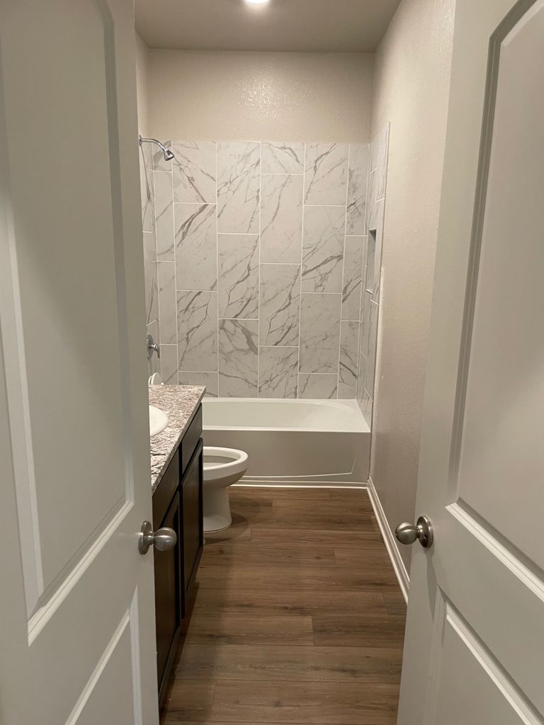 109 Declaration Lane Liberty Hill, TX 78642 - Photo 23 of 24 Bathroom featuring vanity, dark wood-style floors, and washtub / shower combination