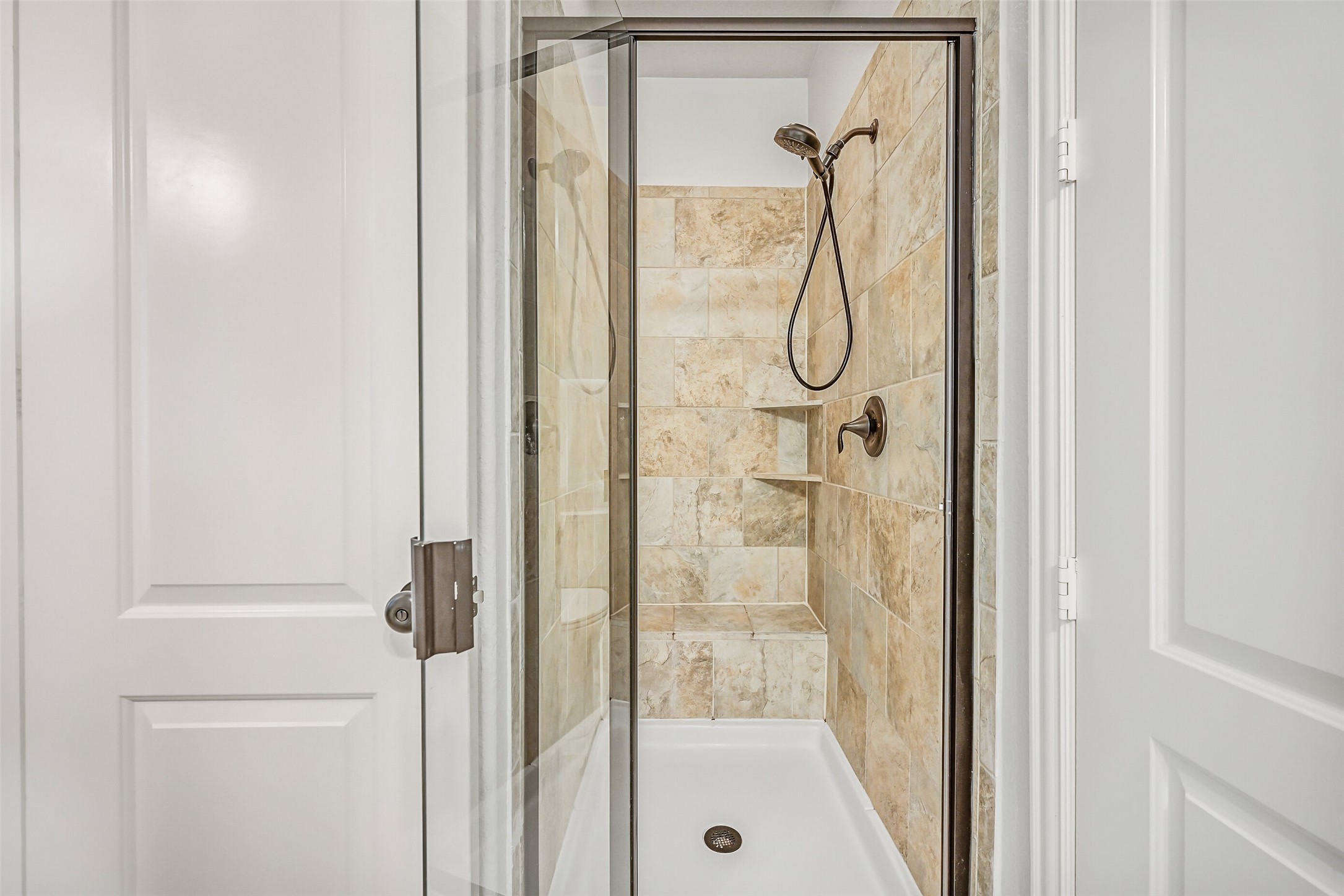 1008 Point Isabel Lane Friendswood, TX 77546 - Photo 27 of 50 The bath includes a tiled walk in shower with glass door and a tile surround with a built in bench seat, as well as a separate water closet, providing both privacy and functionality for daily use.