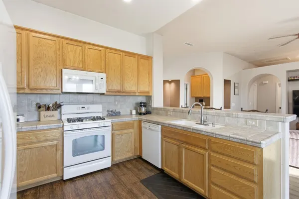 a kitchen with a stove a sink and wooden floor