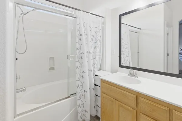 a bathroom with a granite countertop sink a mirror a shower and a bathtub