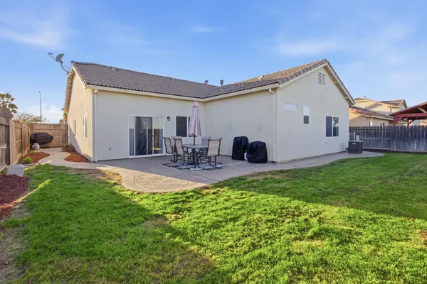 a view of a backyard with table and chairs potted plants and a large tree