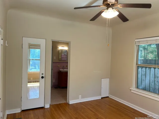an empty room with wooden floor fan and windows