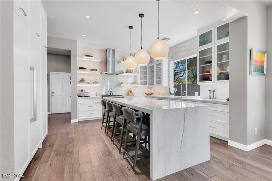 11348 La Madre Ridge Drive Las Vegas, NV 89135 - Photo 18 of 75 Updated chef's kitchen featuring Quartzite waterfall edge island, matching countertops & ceiling height backsplash, Thermador appliances including built-in fridge, island bar and breakfast nook.