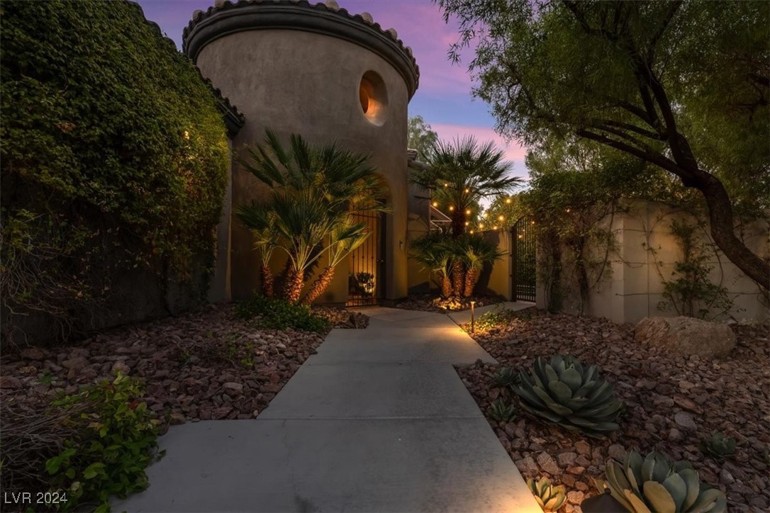 11348 La Madre Ridge Drive Las Vegas, NV 89135 - Photo 41 of 75 Inviting turreted entry leading to a lush courtyard with outdoor lving area and fireplace.