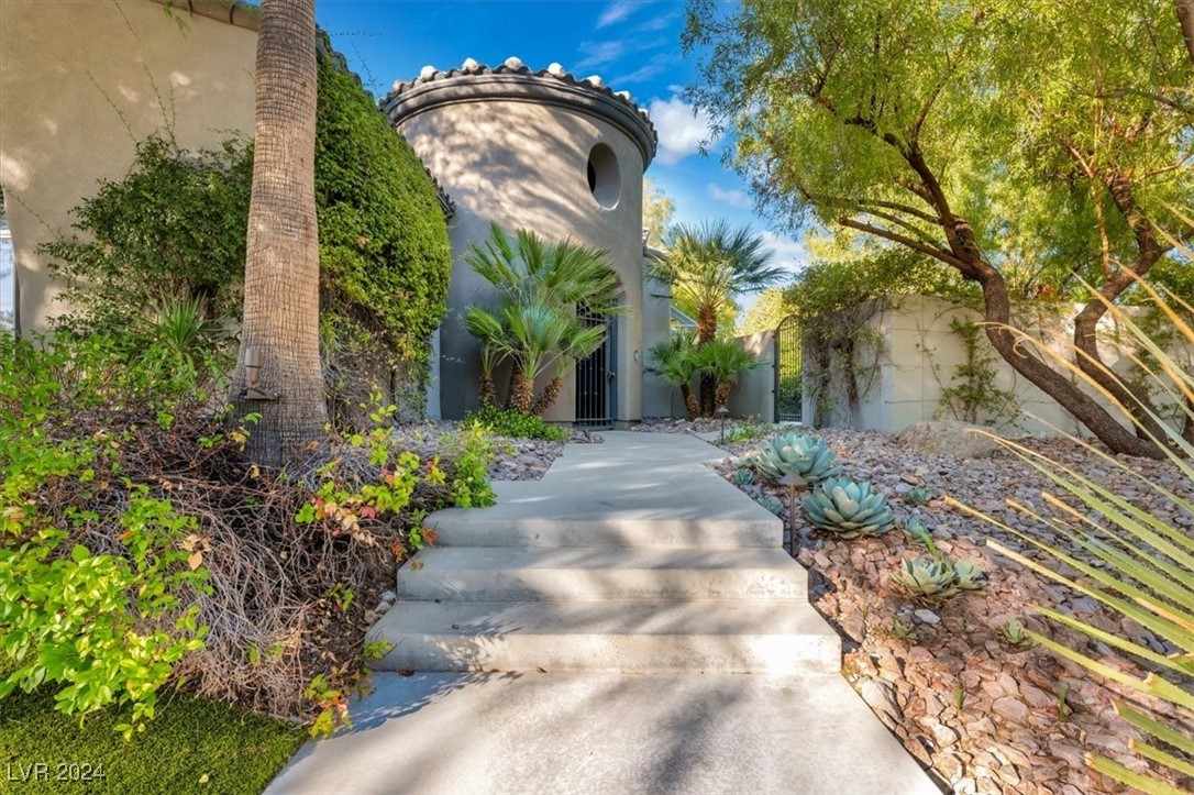 11348 La Madre Ridge Drive Las Vegas, NV 89135 - Photo 59 of 75 Inviting turreted entry leading to a lush courtyard with outdoor lving area and fireplace.