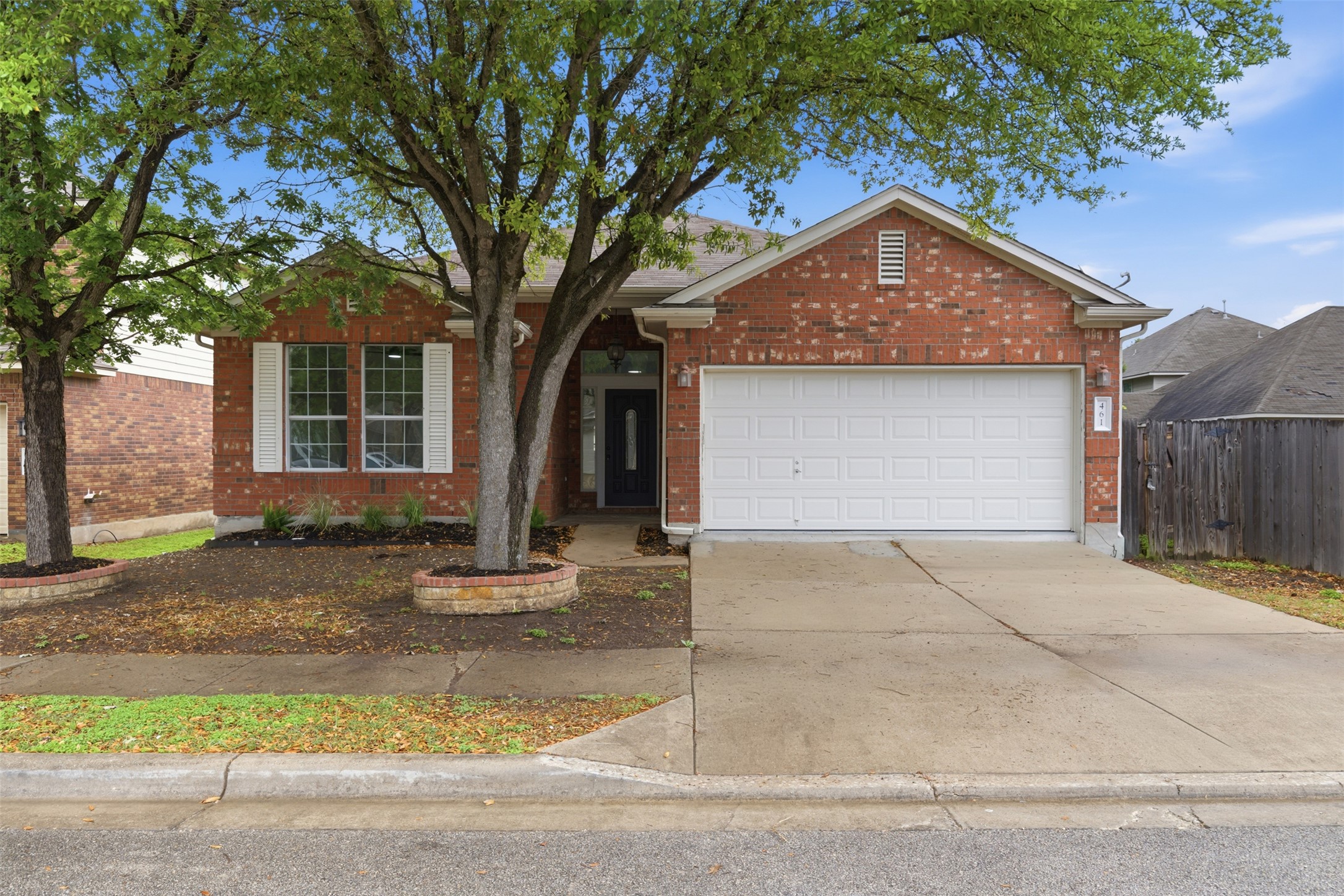 The property features a red brick facade, a two-car garage, and a concrete driveway