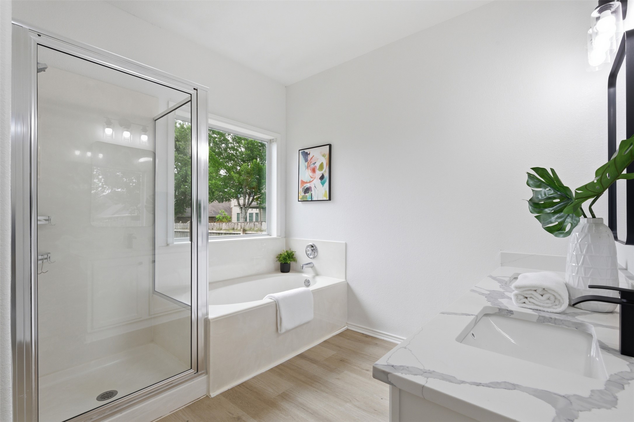 461 Hot Spring Valley Buda, TX 78610 - Photo 17 of 25 Bathroom featuring a walk-in shower with a glass enclosure, a built-in bathtub below a window, and a vanity with a white countertop and integrated sink