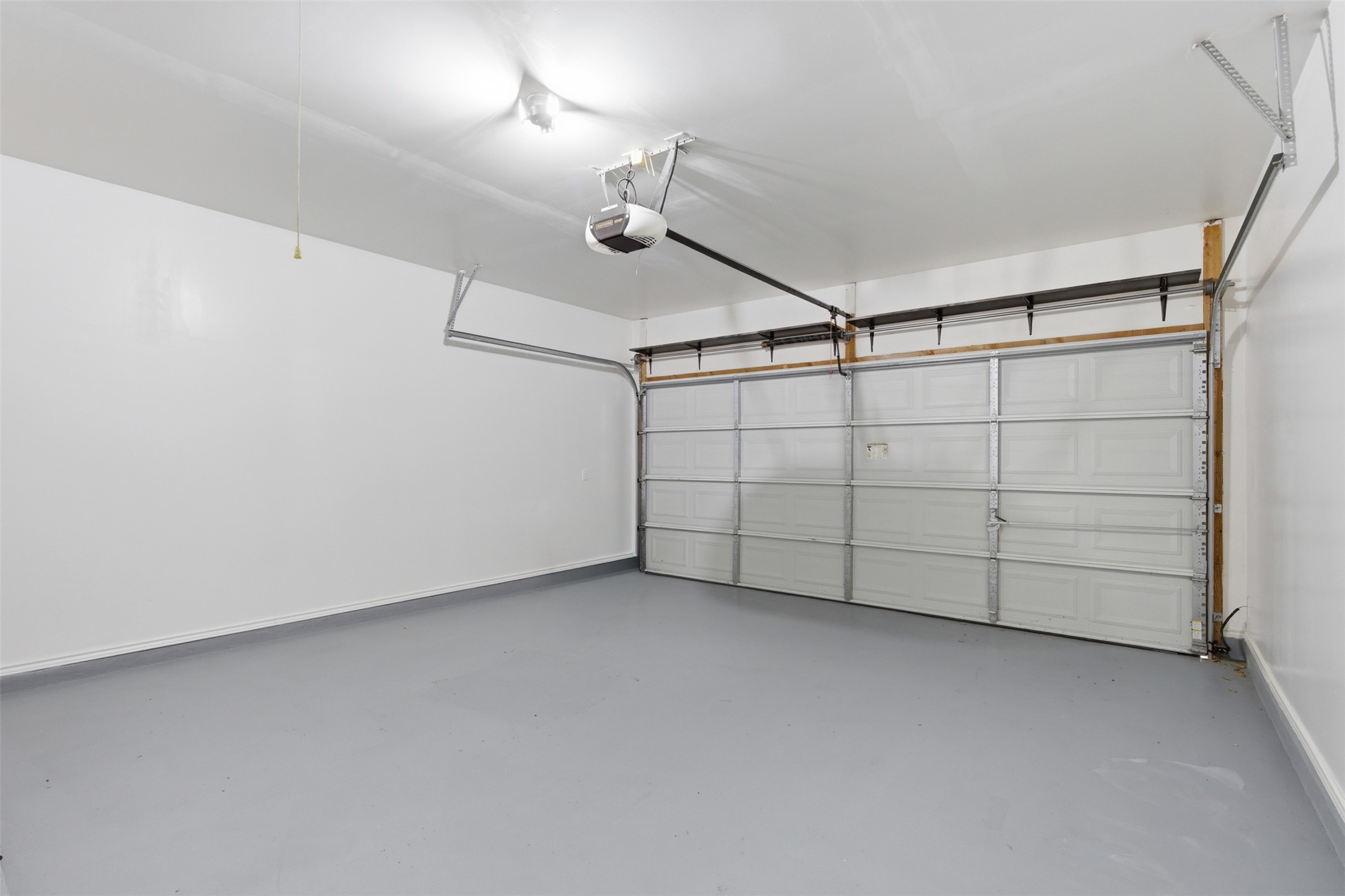 461 Hot Spring Valley Buda, TX 78610 - Photo 22 of 25 The property features a garage with a painted concrete floor, a garage door with an automatic opener, and overhead lighting