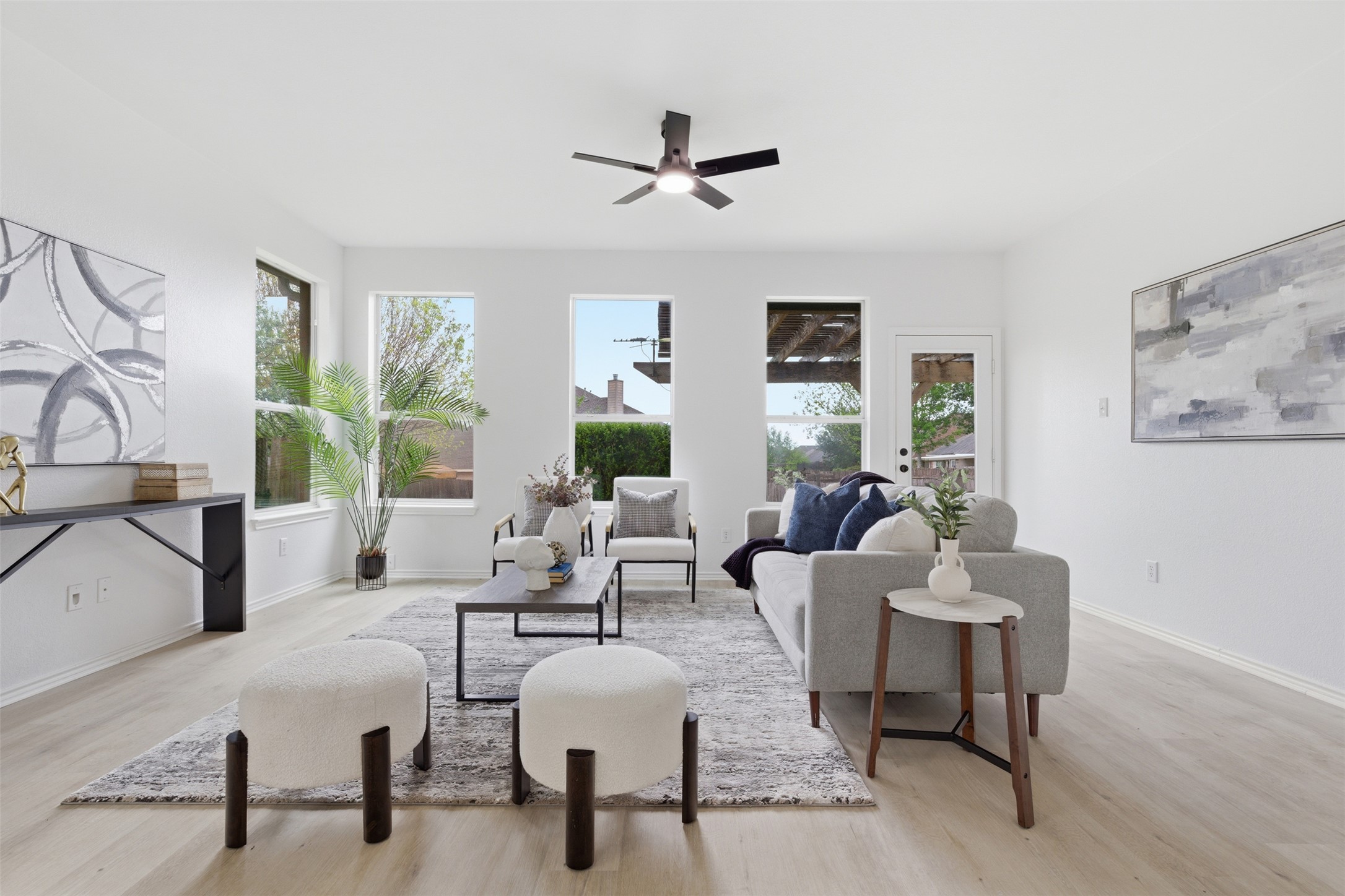 461 Hot Spring Valley Buda, TX 78610 - Photo 3 of 25 Spacious living room featuring light-toned flooring, a ceiling fan, and multiple windows providing natural light