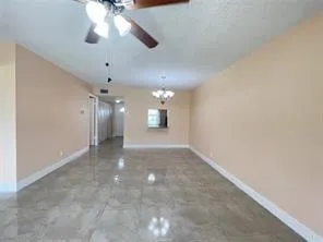 an empty room with a chandelier fan and windows