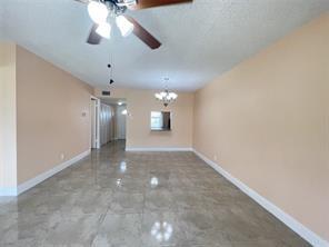 7300 Northwest 5th Court, Unit 106 Margate, FL 33063 - Photo 6 of 13 an empty room with a chandelier fan and windows