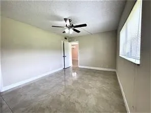 an empty room with a window and a fan