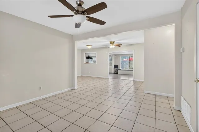 a view of an empty room and chandelier fan