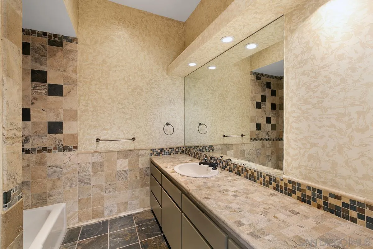 3919 Pringle Street San Diego, CA 92103 - Photo 24 of 37 a bathroom with a granite countertop sink a mirror and shower