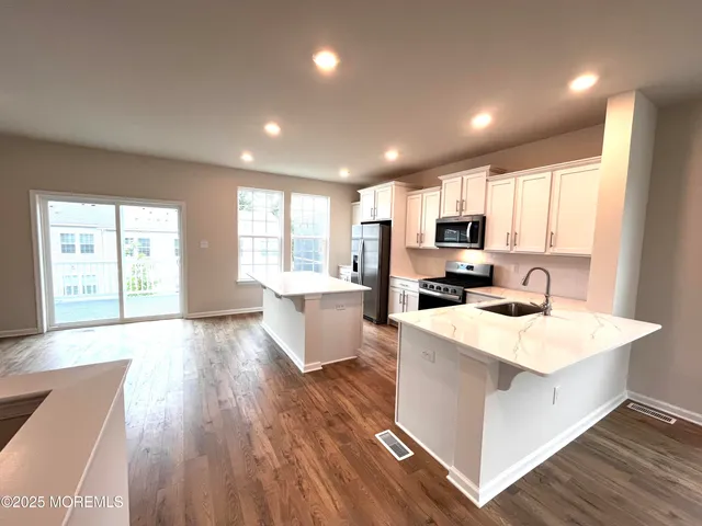a large kitchen with kitchen island a sink wooden floor and white cabinets