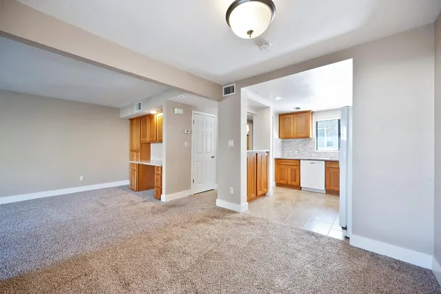an empty room with kitchen view and a window