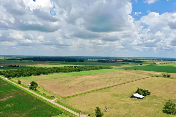 a view of a big yard with an empty space and trees in the background
