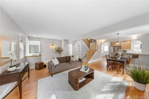 a living room with furniture kitchen view and a wooden floor