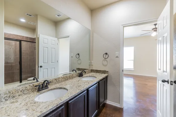 a bathroom with a granite countertop double vanity sink and a mirror
