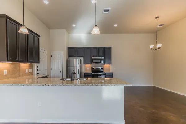 a kitchen with stainless steel appliances granite countertop a sink refrigerator and cabinets