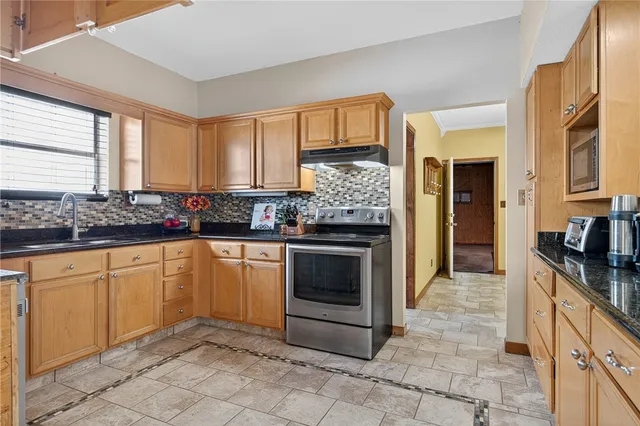 a kitchen with stainless steel appliances granite countertop a stove a sink and a refrigerator