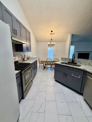 a kitchen with stainless steel appliances granite countertop a stove a sink and a refrigerator