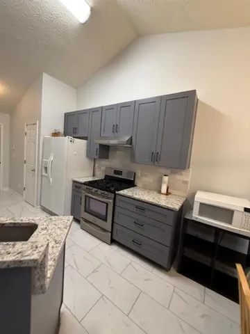a kitchen with granite countertop a sink stove and refrigerator